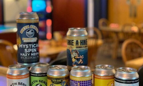 Various cans of beer on display on a bar.