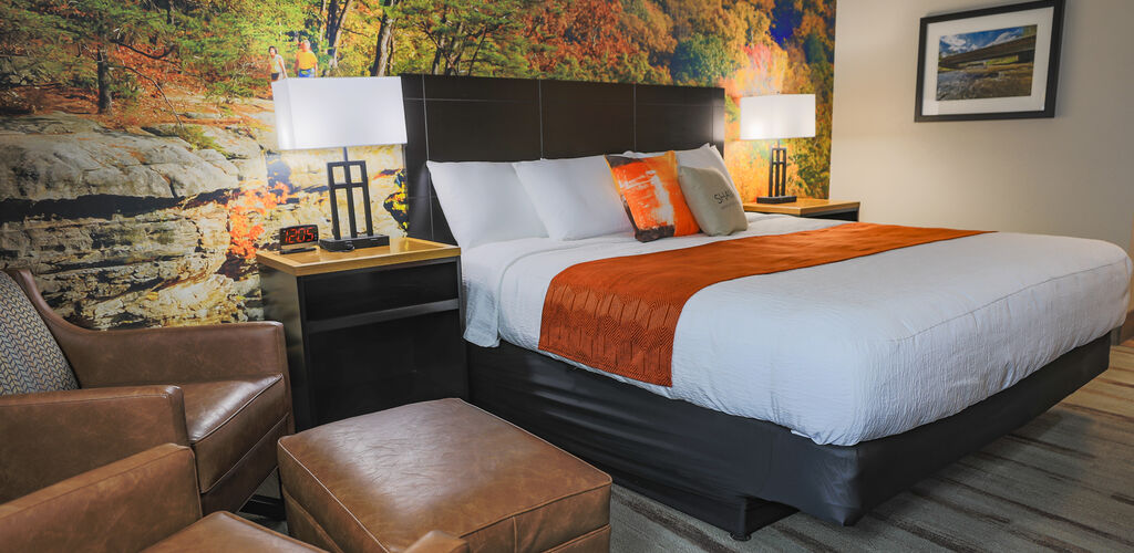 A mural is situated behind a king bed in a room at Shawnee State Park Lodge