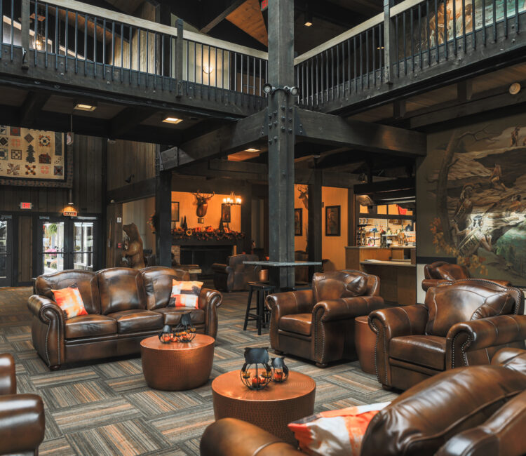 Lobby with leather furniture at the center. In the background is the front desk. There's a mural of native americans on one wall. 