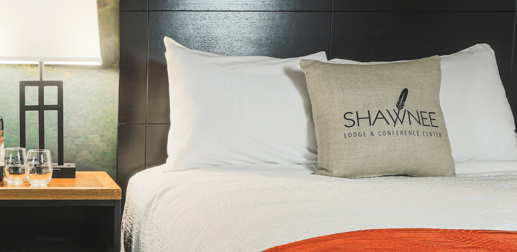 Two queen beds with a table in the middle. On the table is two wine bottles and wine glasses.